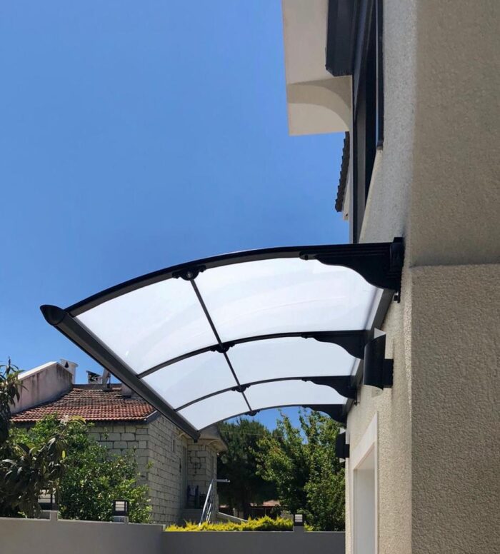 Curved transparent canopy mounted to the exterior beige wall, shielding a doorway.